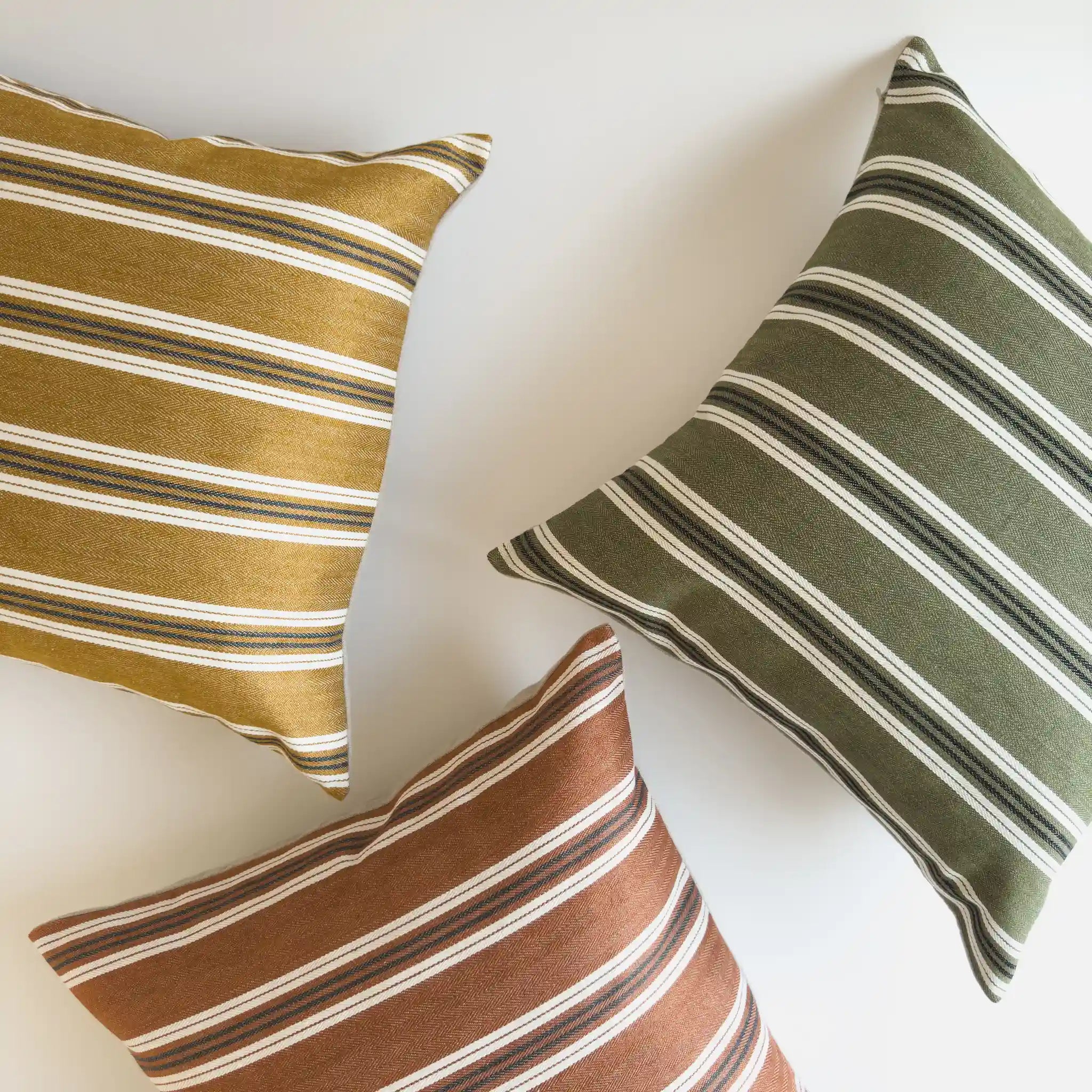 Colourful striped cushions in mustard, olive and rust