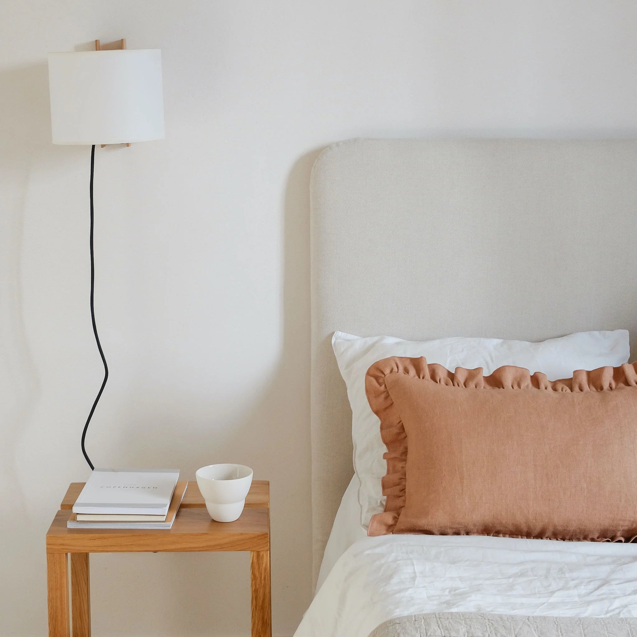 Light brown linen frill cushion styled on bed