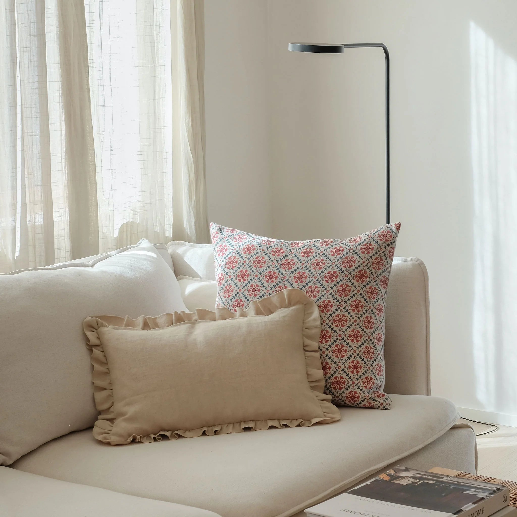 Red and blue floral cushion on a sofa with a cream frill cushion