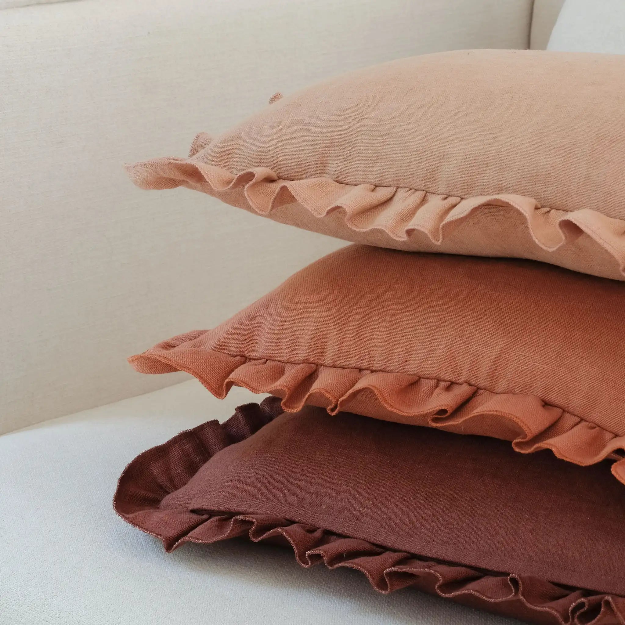 Stacked linen ruffled cushions in burgundy, terracotta and clay