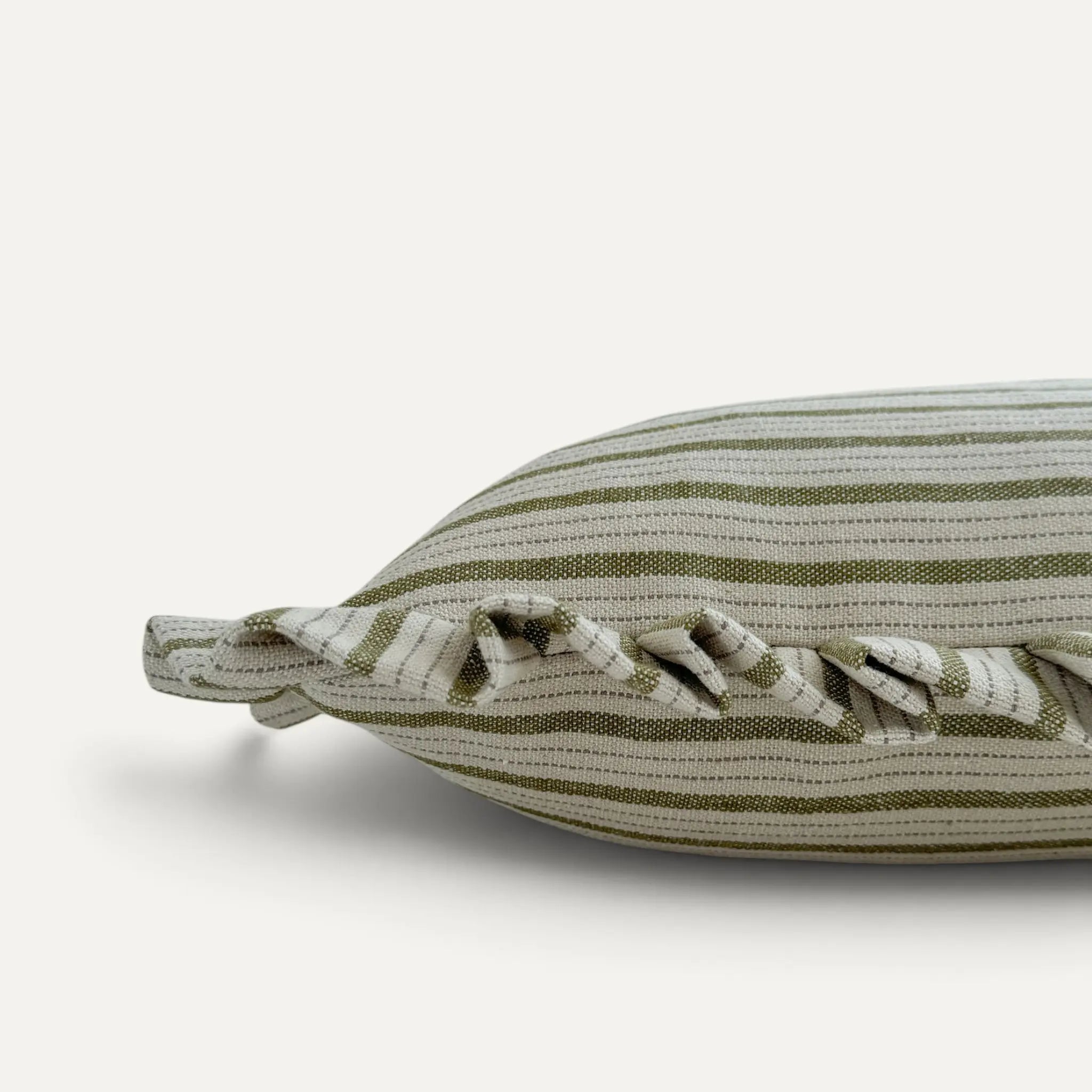A close-up of a striped throw pillow in olive green and cream linen fabric, featuring a ruffled edge detail, set against a plain off-white background.