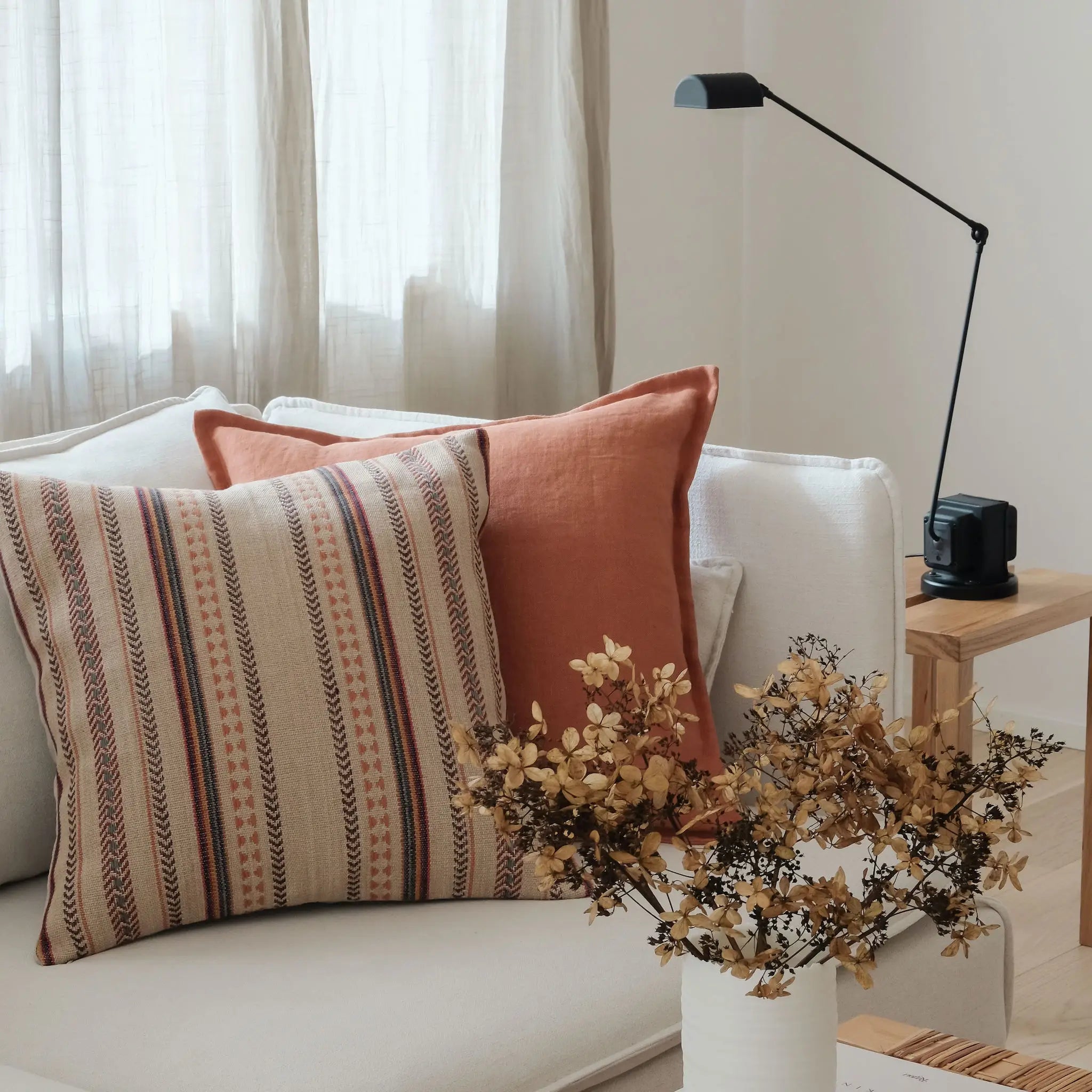 Terracotta linen and natural patterned cotton and jute cushions styled on a white sofa