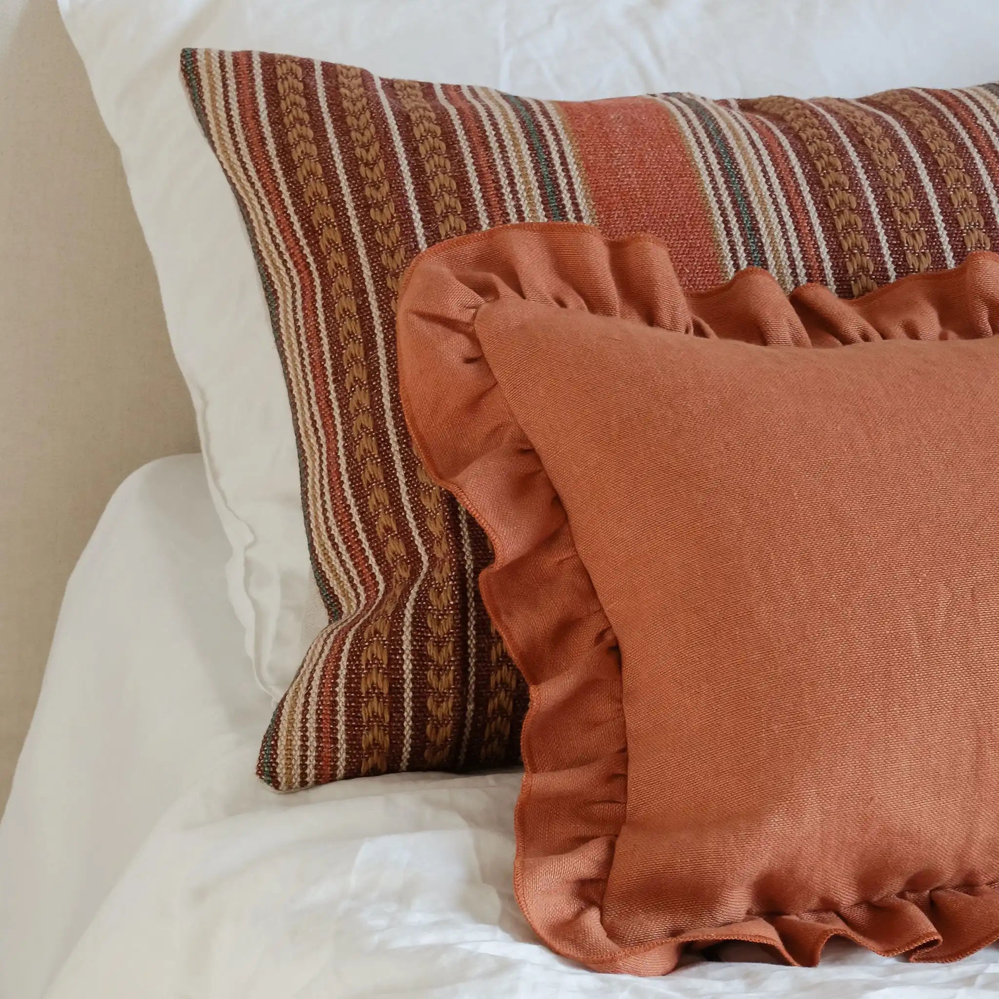Terracotta and burnt orange cushions styled on bed