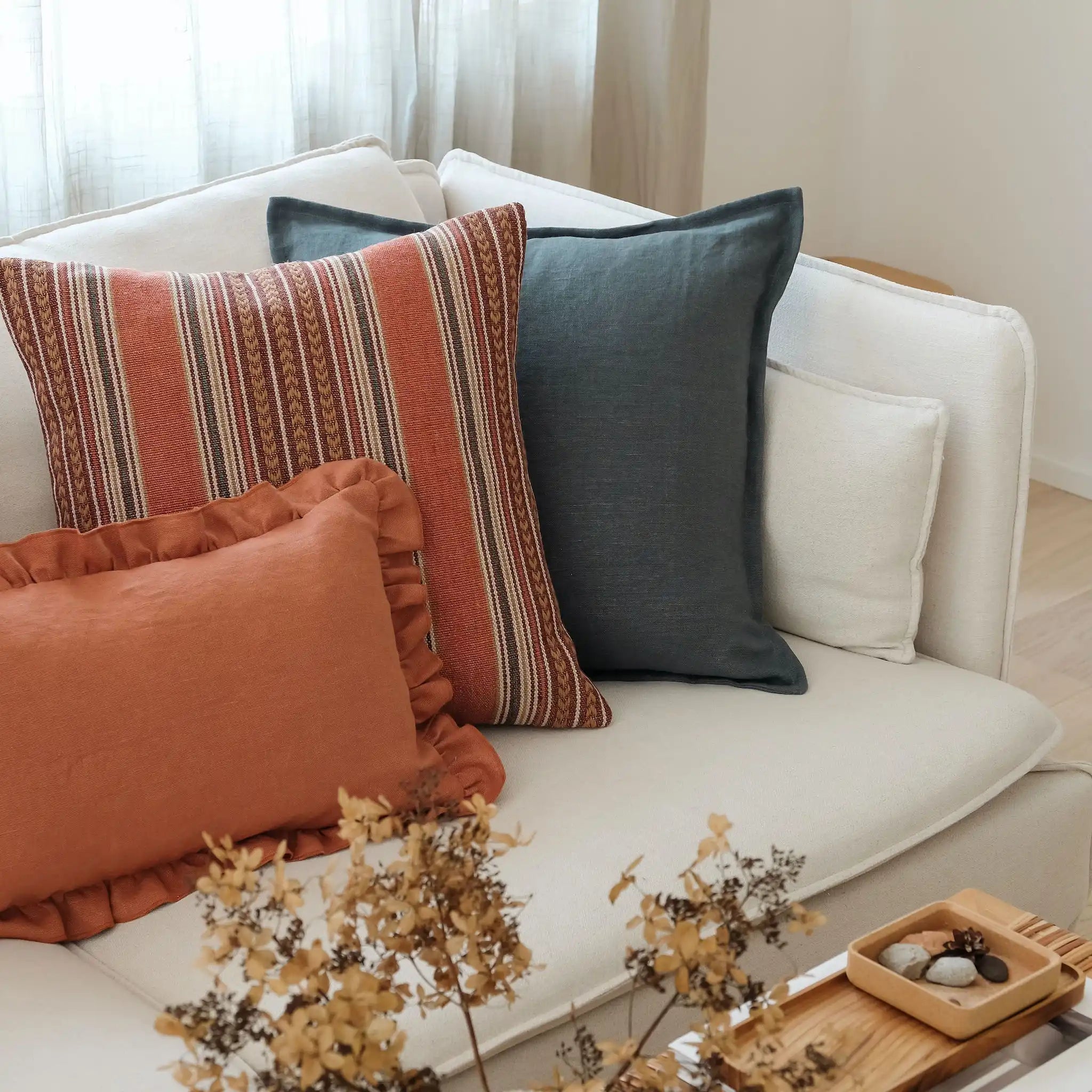 Rust, terracotta and teal cushions styled on a white sofa