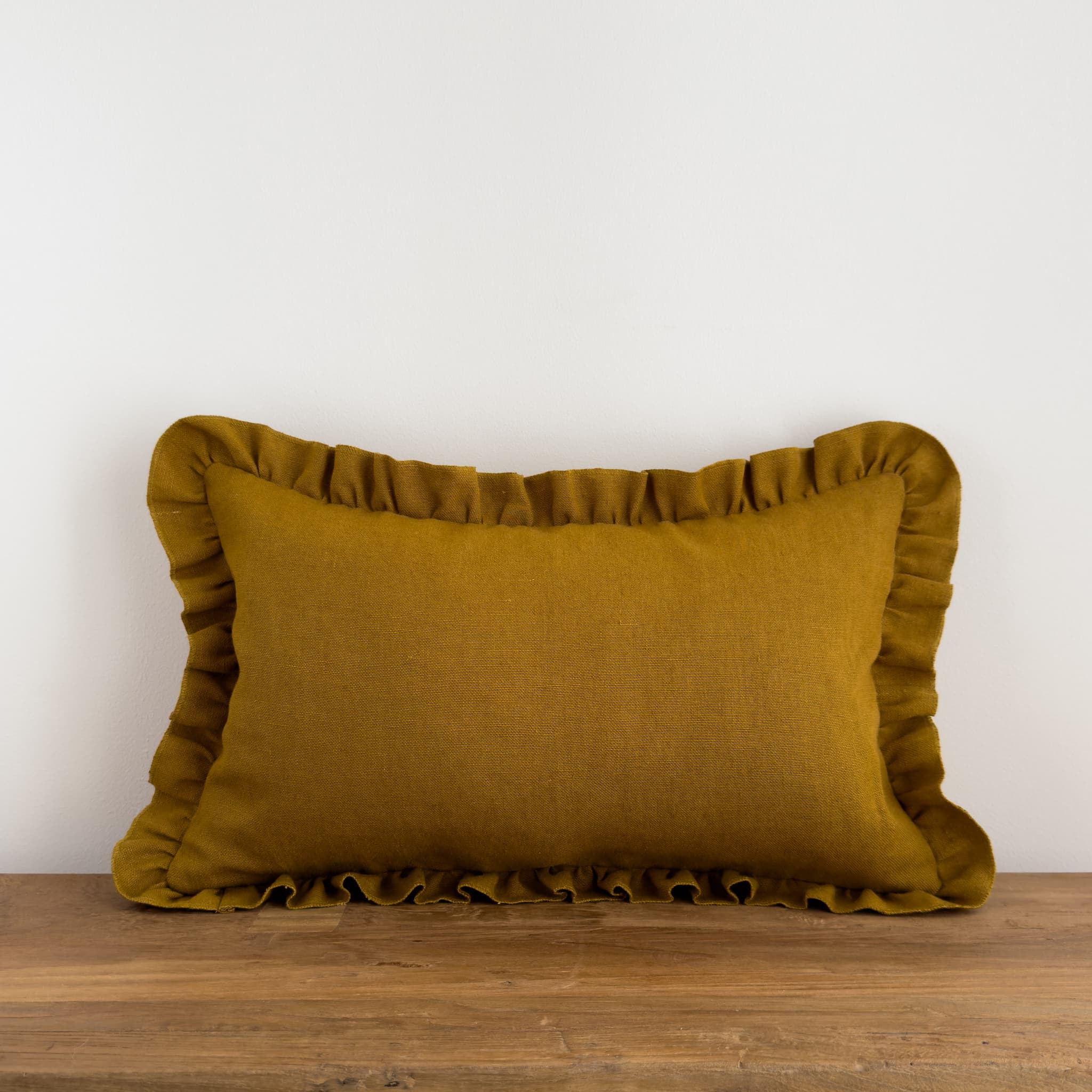 Mustard frill cushion on a rustic wood bench