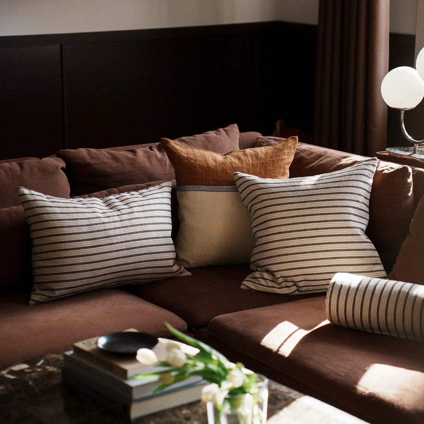 Black and white striped cushions on a cosy contemporary brown sofa