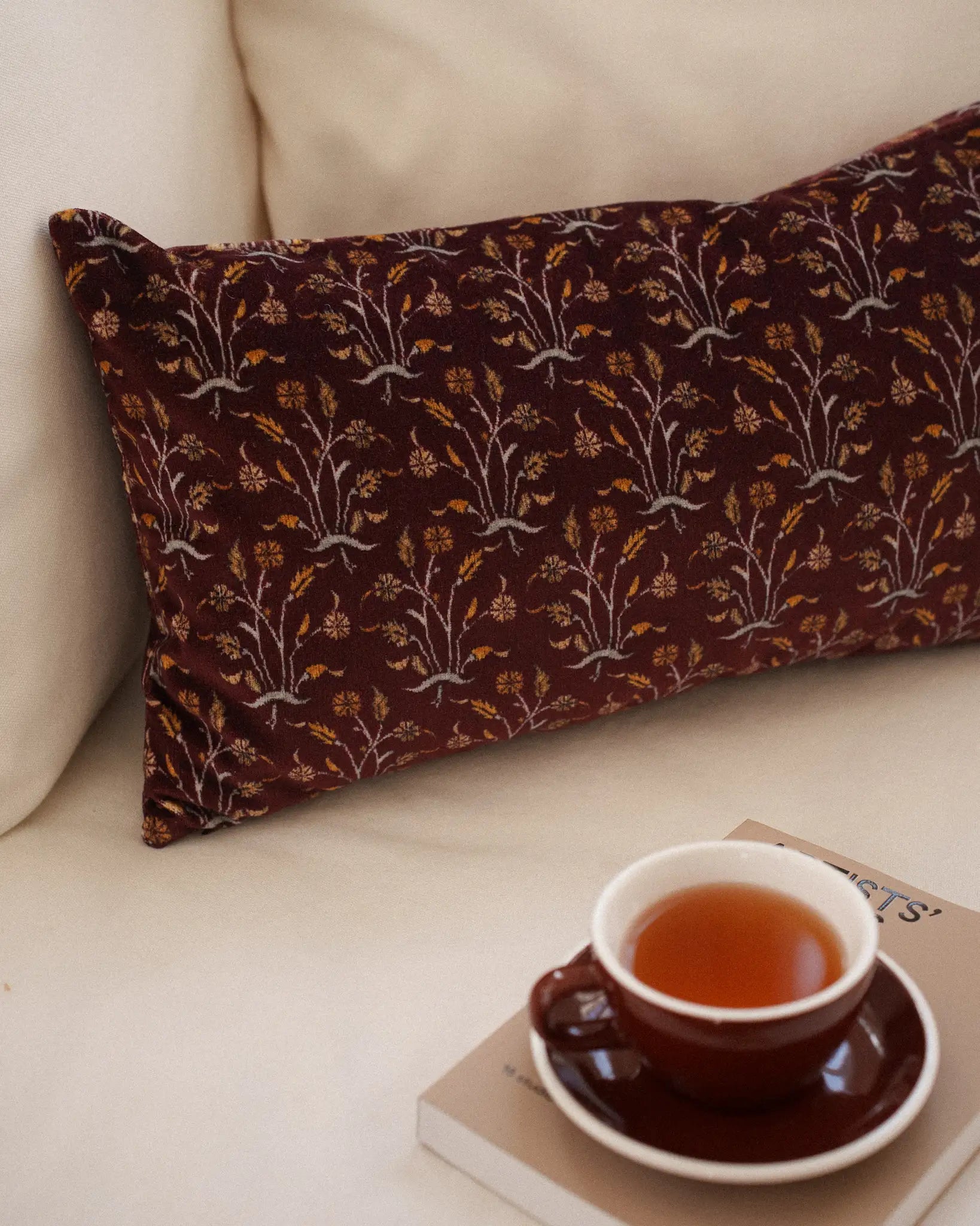 Floral burgundy velvet cushion on a sofa