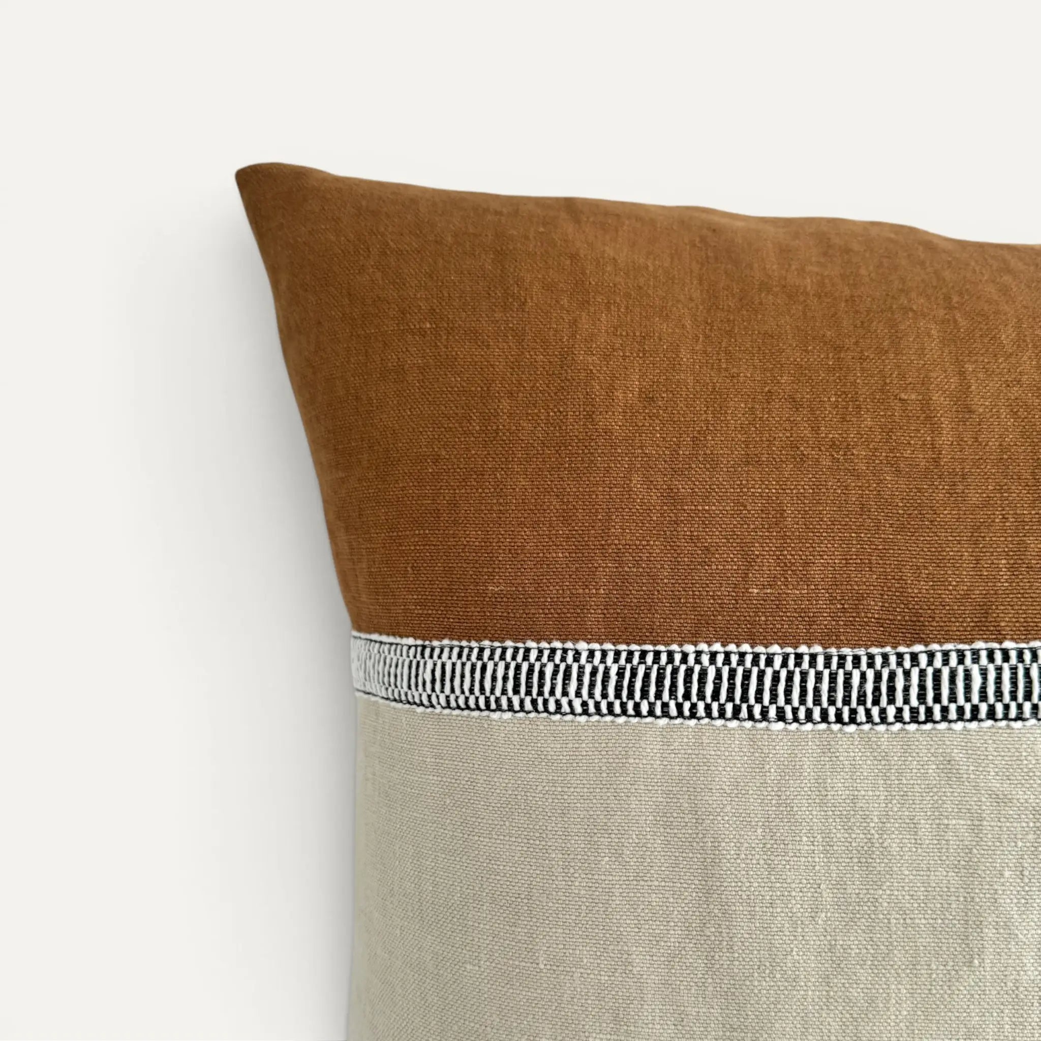 Detail view of cream and brown linen cushion cover with black and white striped decorative ribbon