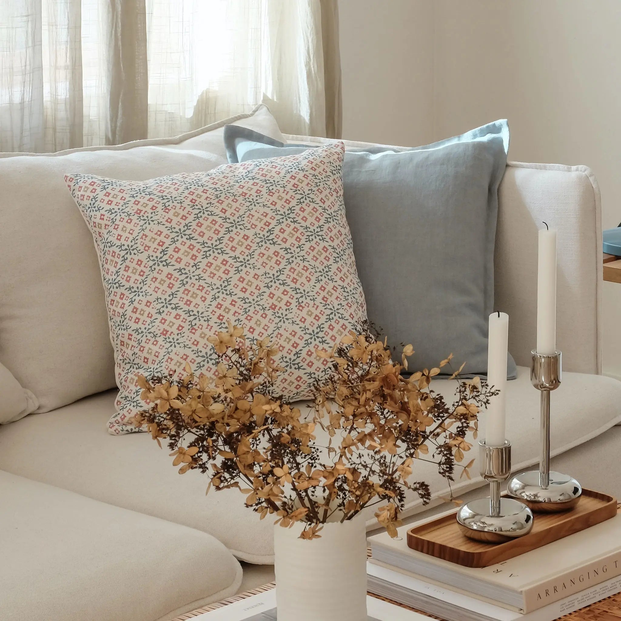 Duck egg blue linen cushion and colourful floral cushion with blue and red styled on a white sofa