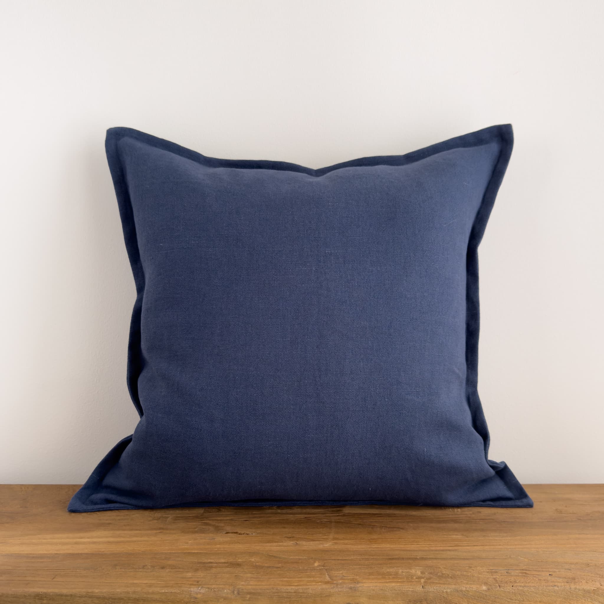Navy blue stonewashed linen cushion on a rustic wood bench