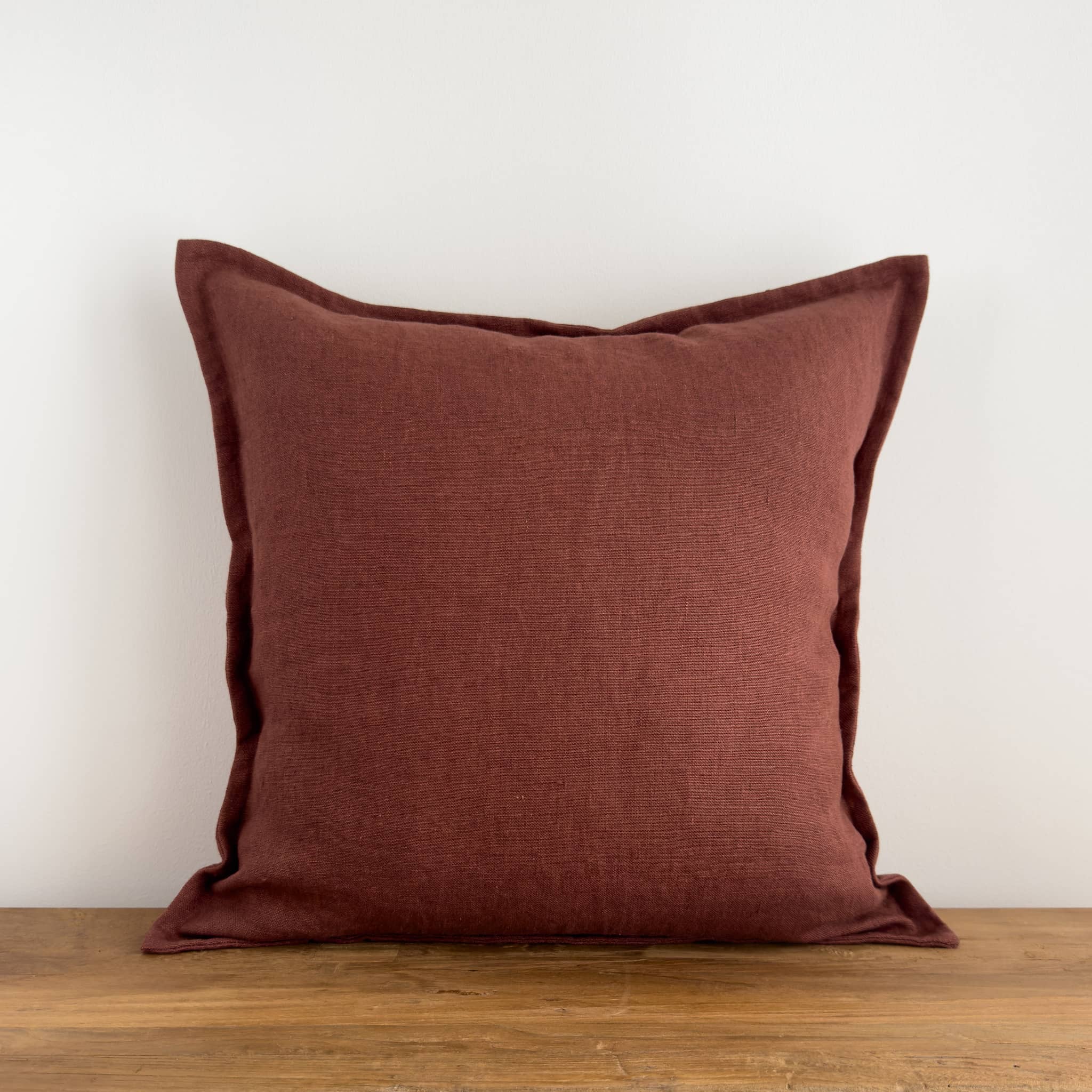 Burgundy red linen cushion on a rustic wood bench