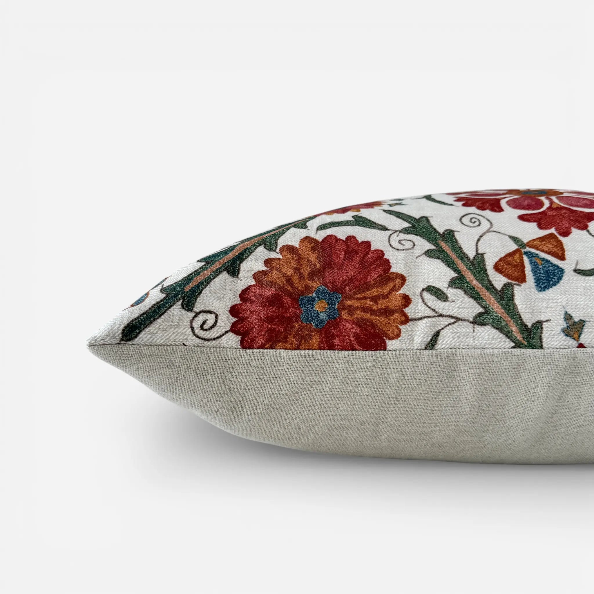 Side view of floral Suzani linen cushion cover with red floral detail and natural linen reverse