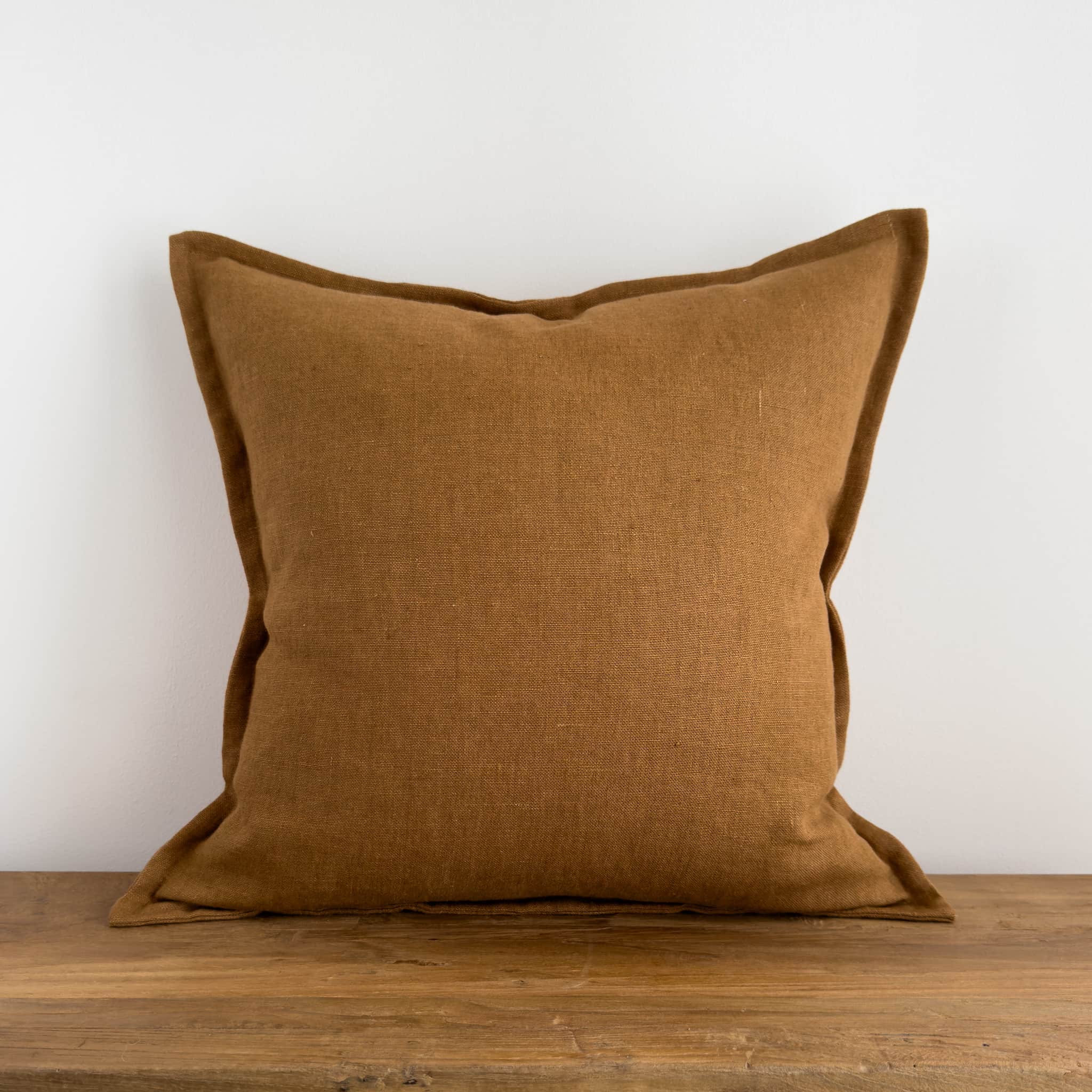 Brown stonewashed linen cushion on a rustic wood bench