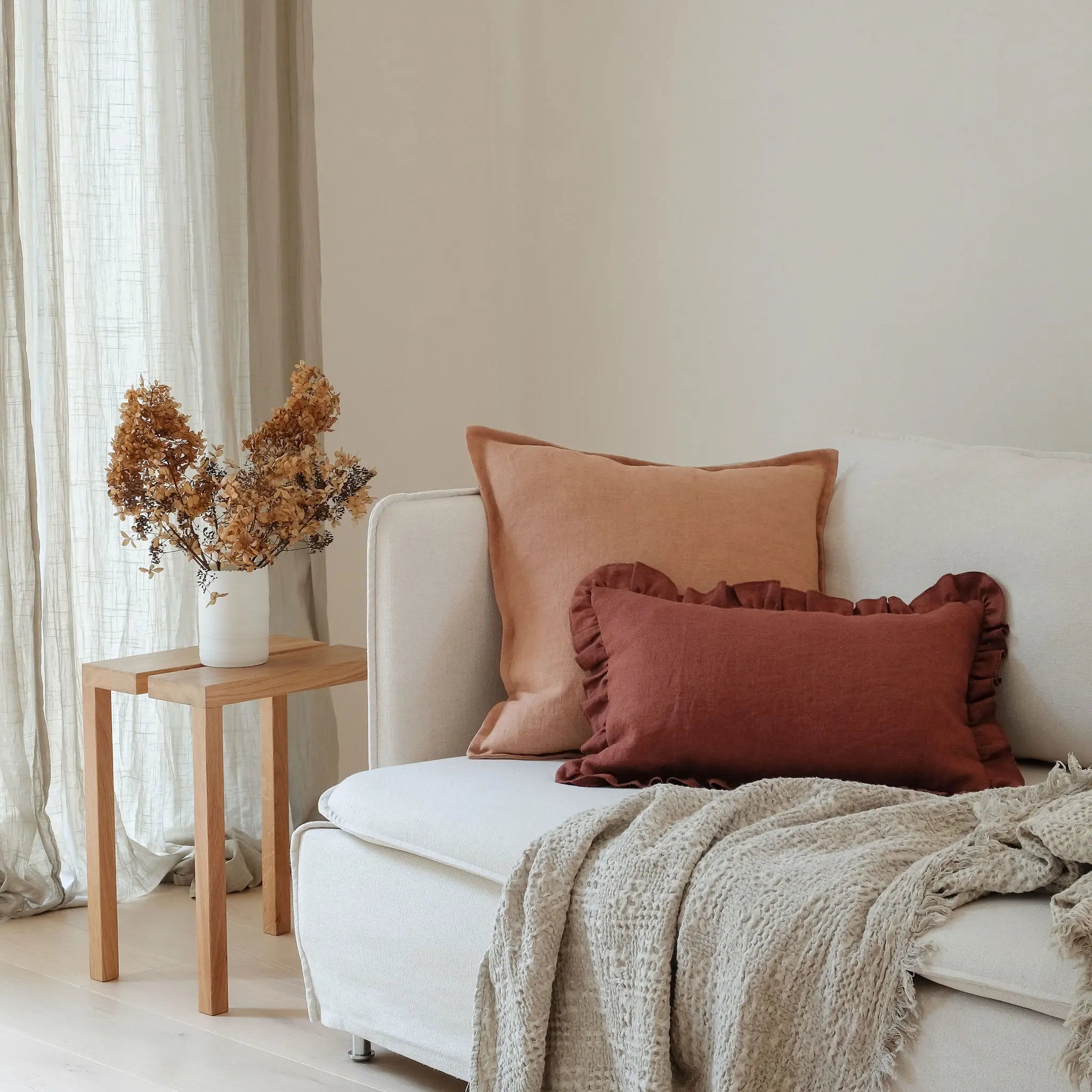 Clay brown and burgundy cushions styled on a white sofa with a neutral throw