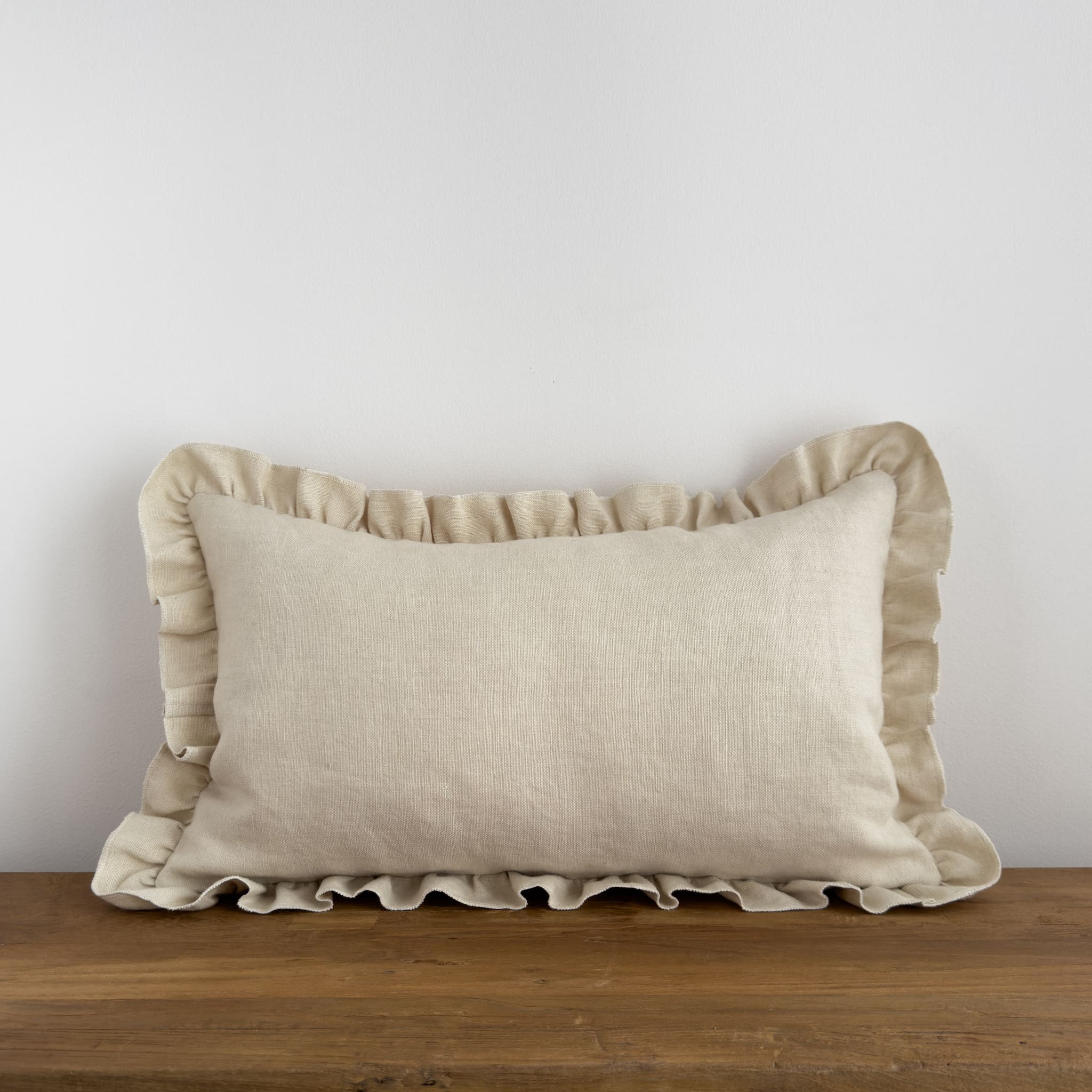 Cream ruffle cushion on a rustic wood bench